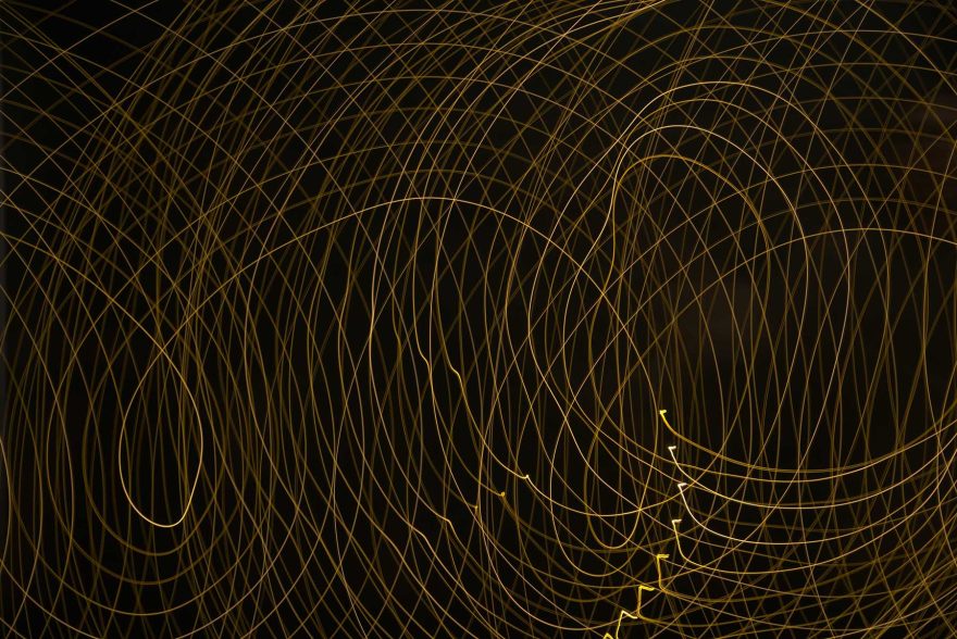 golden lines wrapping around each other and spreading out on a black background
