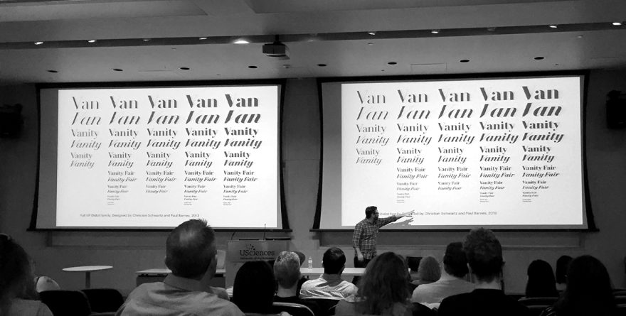 Christian Schwartz pointing to a projection of various font examples while lecture attendees look on