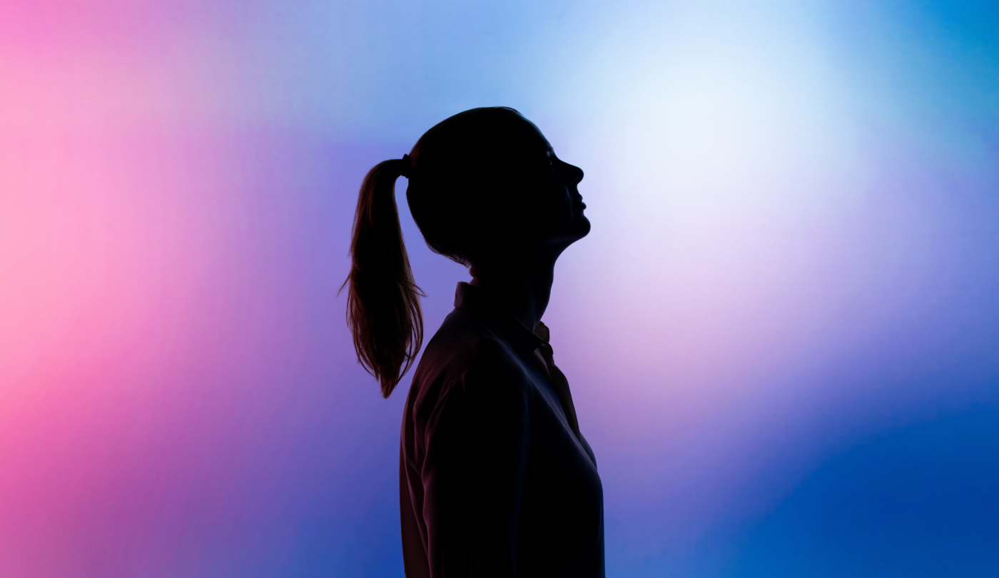 the silhouette of a woman looking up in front of a gradient background