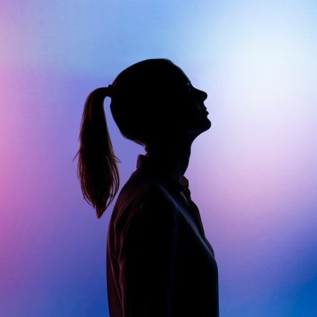 the silhouette of a woman looking up in front of a gradient background