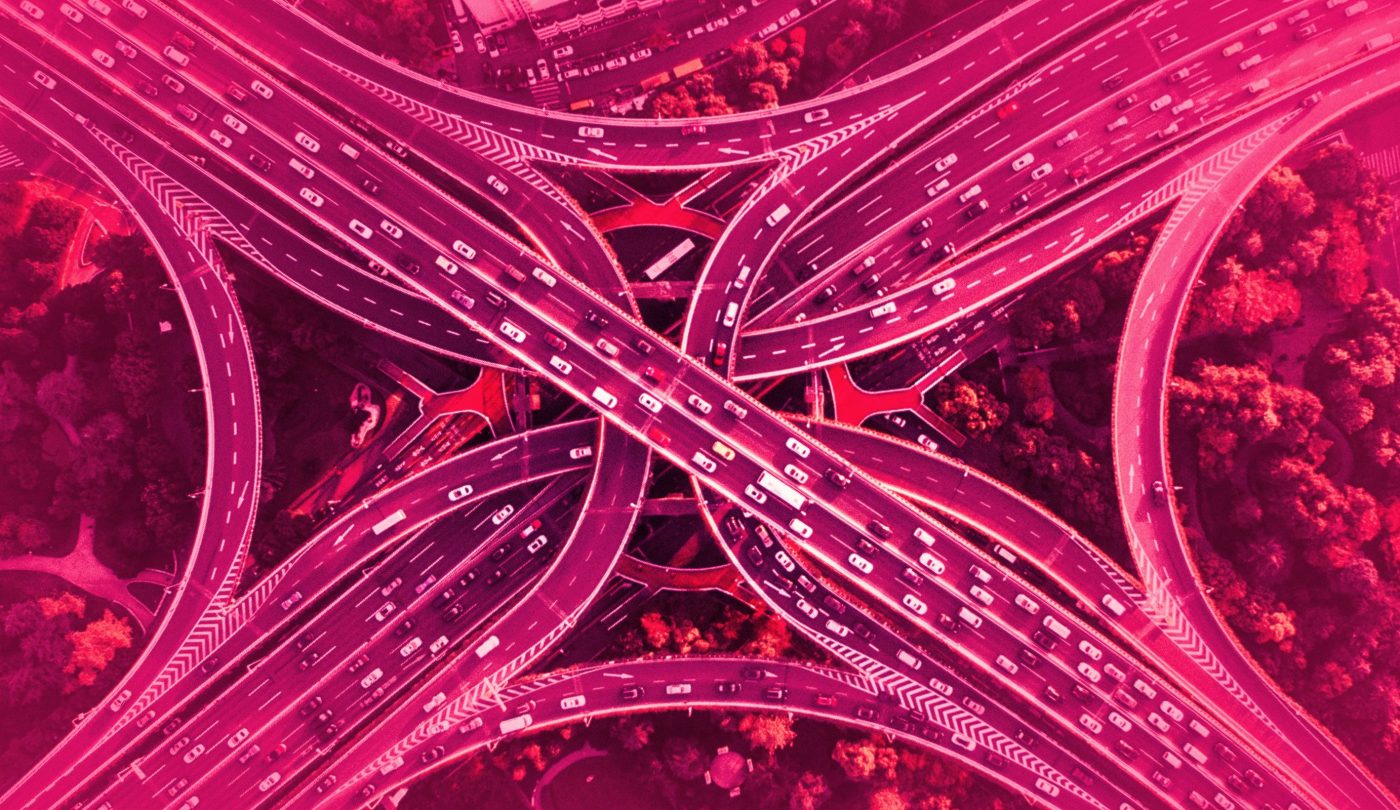 Artistic photo of a highway cloverleaf interchange with a rose-colored overlay.