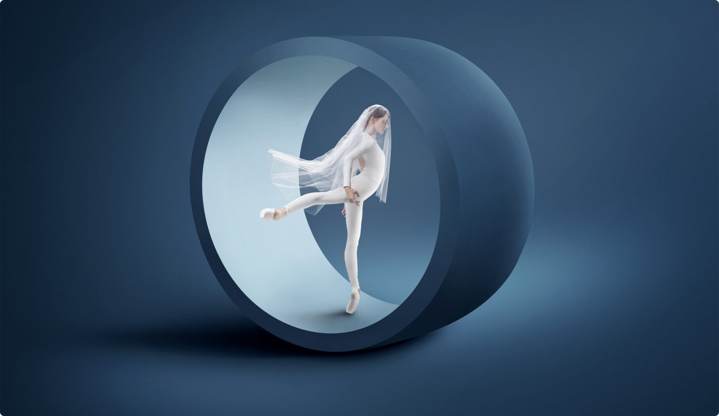 A ballerina en pointe dressed in all white standing in a sculptural wheel highlighting the beauty and drama represented by the Philadelphia Ballet branding campaign.