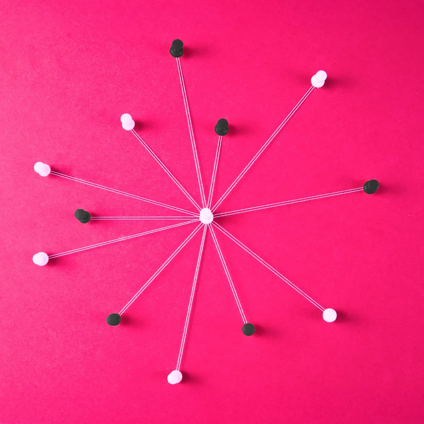 An abstract representation of a centralized network: a white pin at the center connects to multiple black and white pins around it using strings, symbolizing interconnected systems on a vibrant pink background.