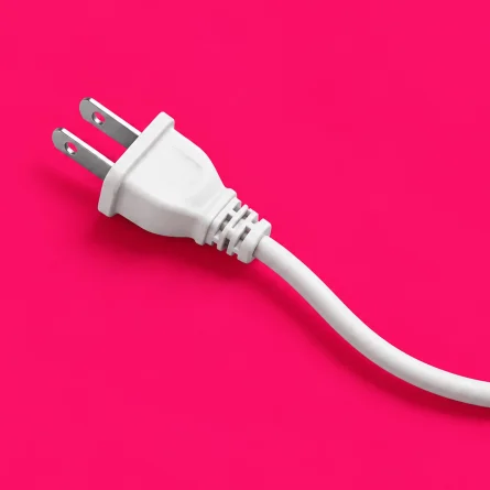 White electrical plug with a curved cord on a bright pink background.