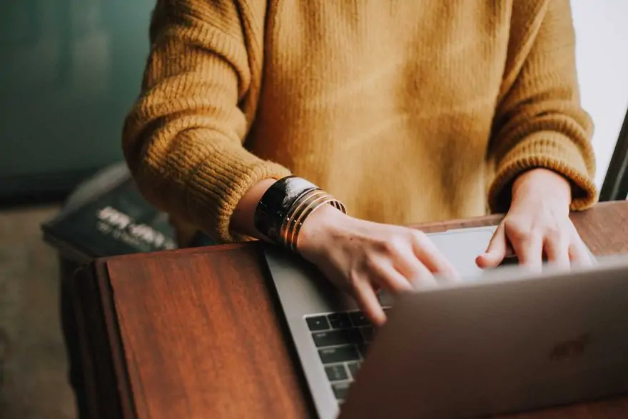 a woman's hands typing on a laptop