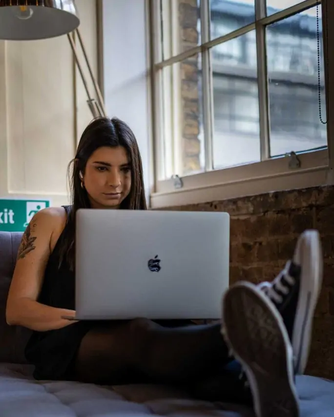 a young woman working on a laptop on her couch