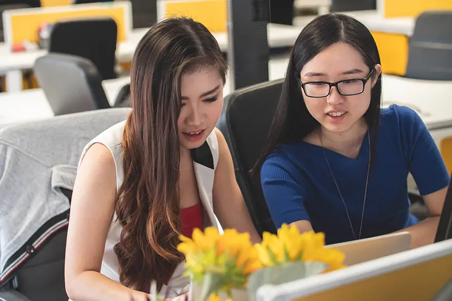 two young women working together on a laptop