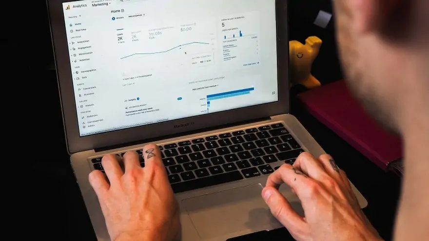 a young man's hands over a laptop keyboard with Google Analytics on the screen