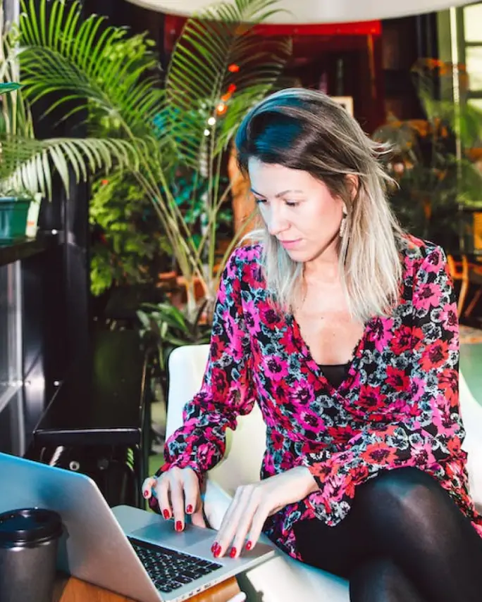 a woman typing on her laptop surrounded by plants