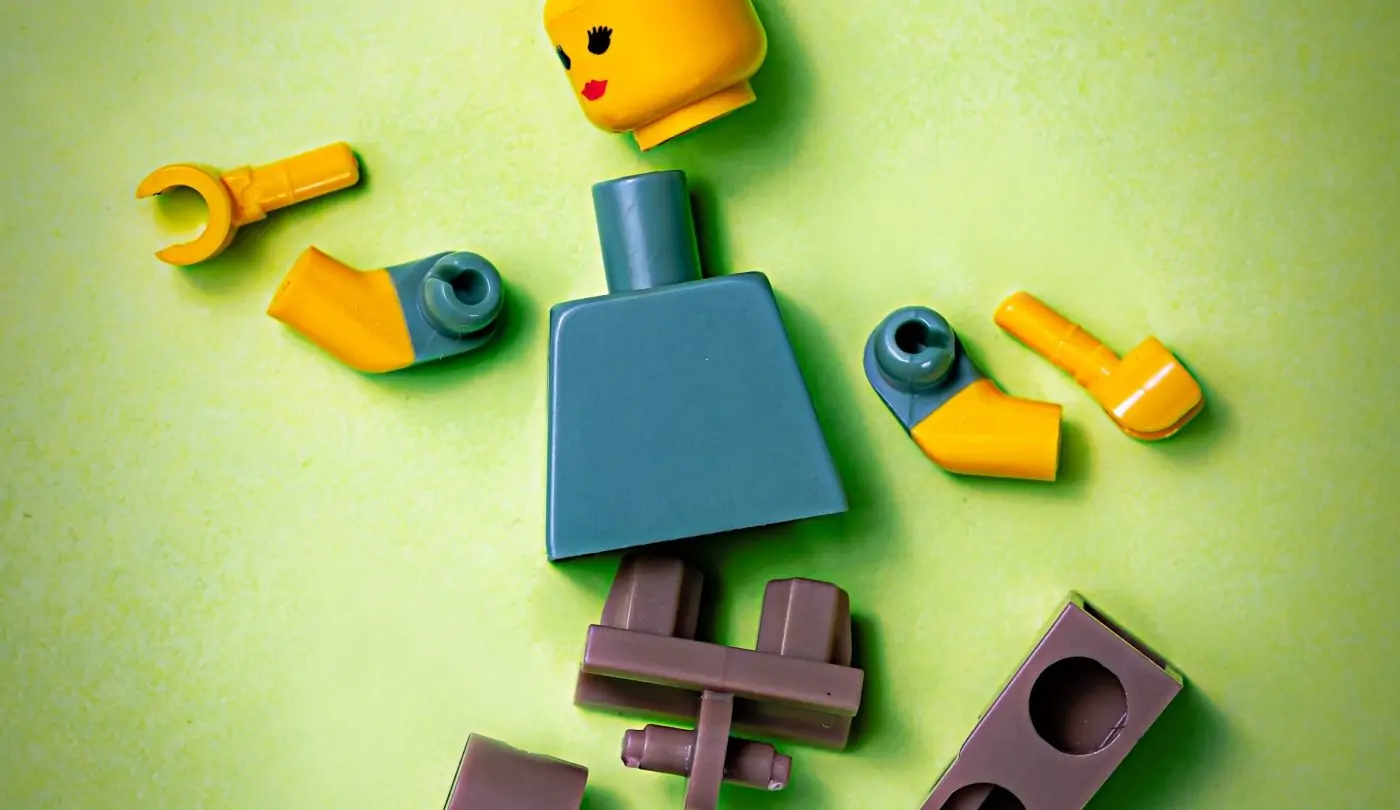 A lego figure lays disassembled with parts strewn around it