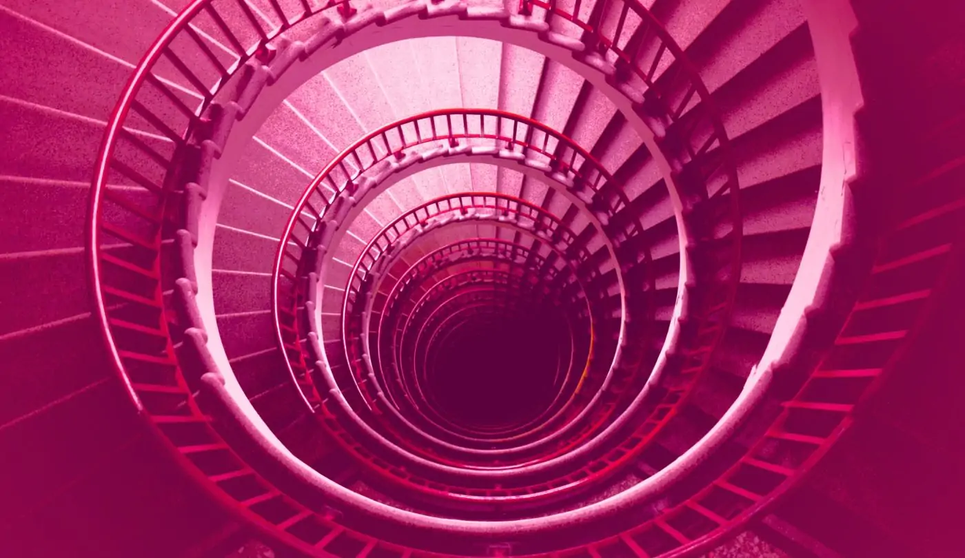Photograph capturing a spiral staircase, viewed from a top-down perspective and immersed in a vibrant rose hue.