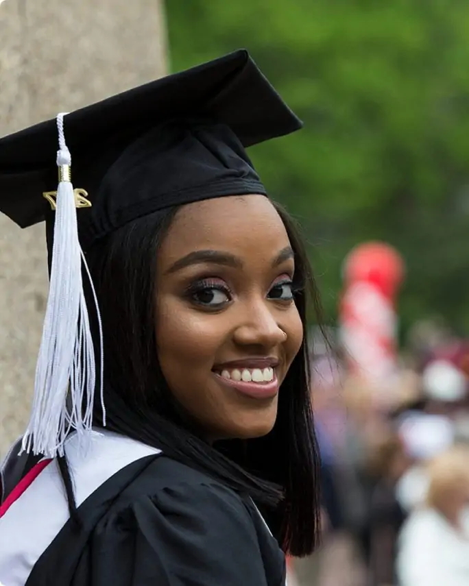 Temple graduate smiling during the graduation ceremoly in their cap & gown