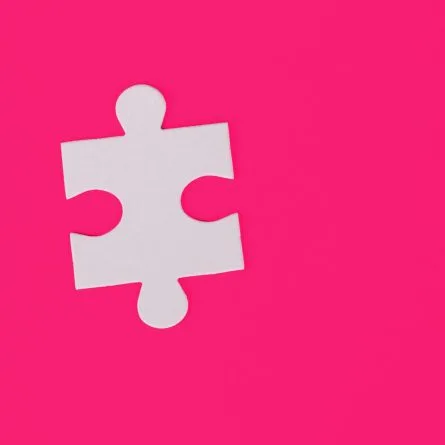 A white puzzle piece on a pink background