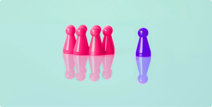A group of seven pink pawn opposite a purple pawn standing on a reflective green surface