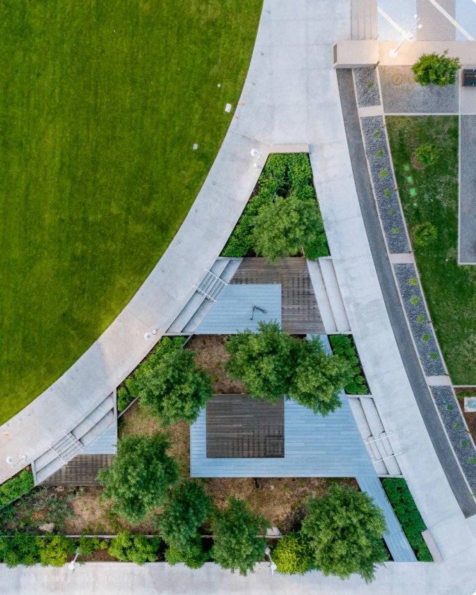 Aerial view of the University of Colorado Denver campus, featuring a large green lawn, walking paths, and landscaped seating areas with trees and modern architecture.