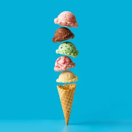 Stacked scoops of colorful ice cream floating above a waffle cone on a bright blue background, representing the layered approach of full-service digital agency services, from strategy and UX to development, SEO, and ongoing optimization.