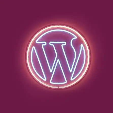 WordPress neon sign glowing in blue and pink light against a deep magenta background, representing a WordPress design agency